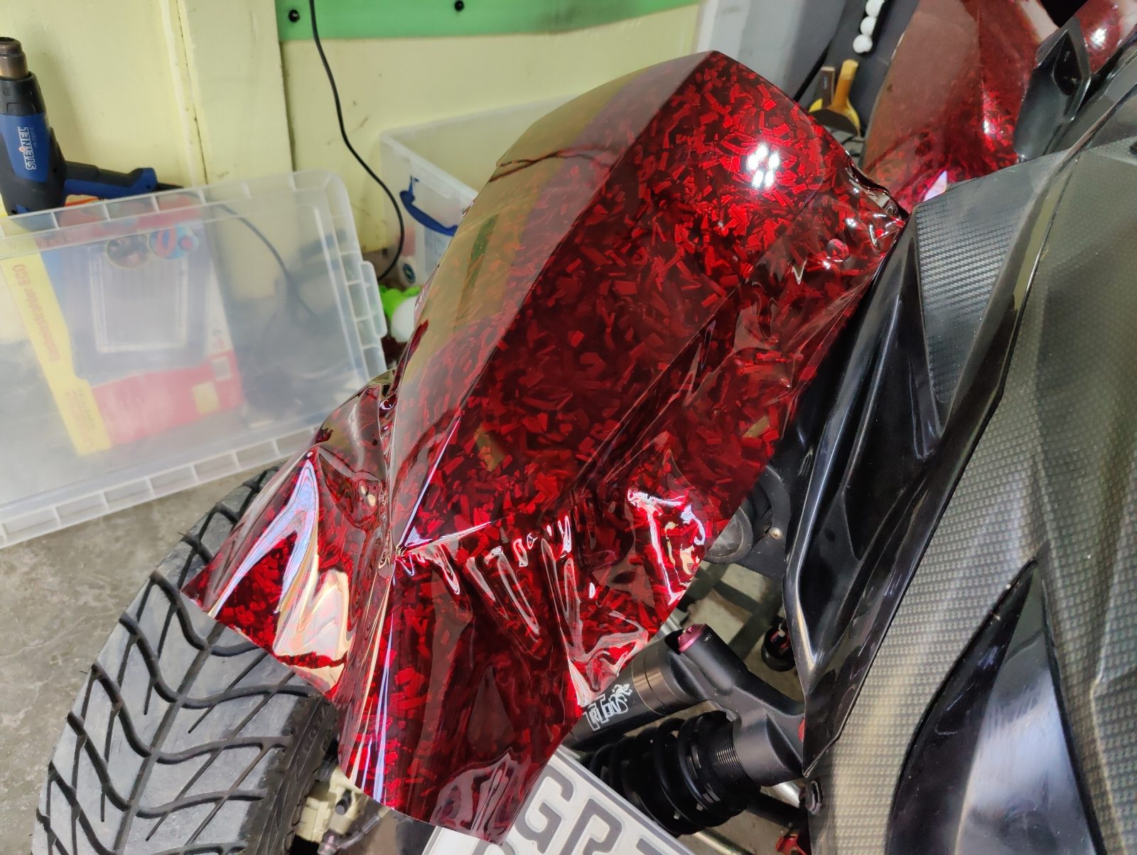 Quad-Hinterrad mit roter Effektfolie auf dem Kotflügel Detailaufnahme eines folierten Quad-Kotflügels mit roter Splitter-Effektfolie, glänzend und blasenfrei appliziert