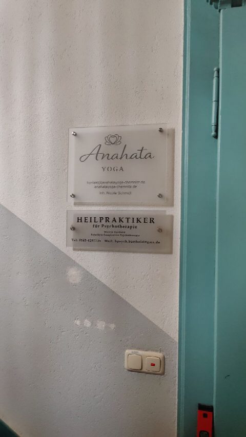 Nahaufnahme des neuen Anahata Yoga Schildes neben dem Schild eines Heilpraktikers